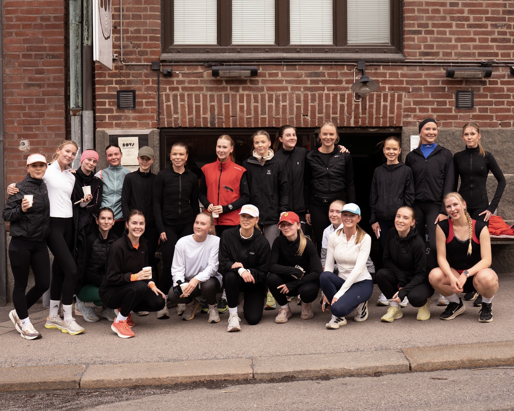 Tjejerna i Core Run Club står samlade utanför ett rödbruna tegelhus i Göteborg