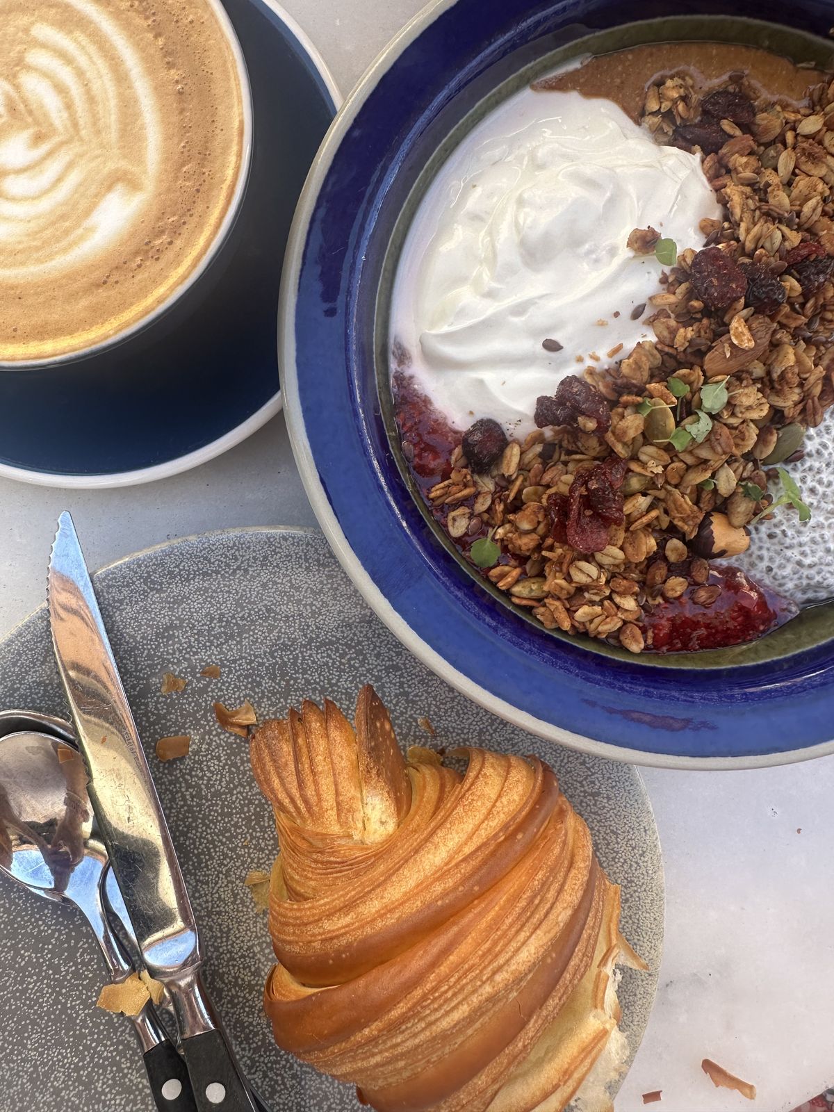 Frukostbowl med yoghurt och granola, en croissant och cappuccino på Pascal