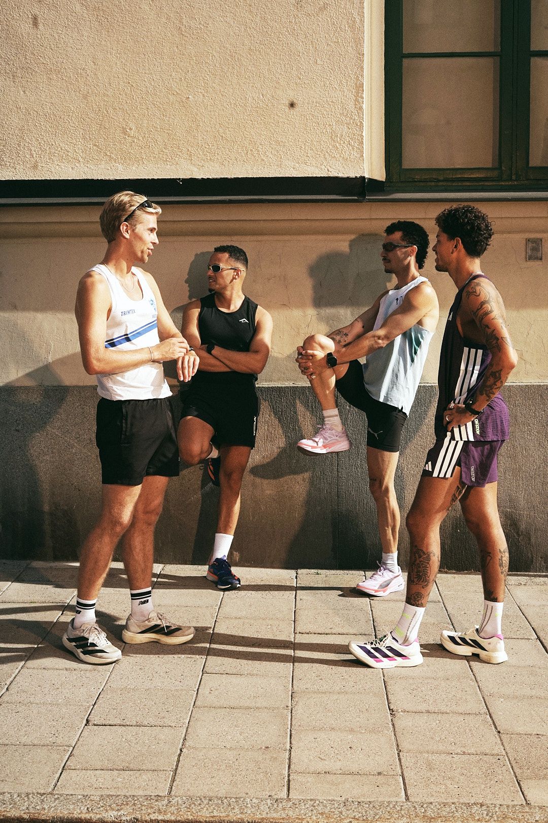 Fyra löpare från Mile Makers står och pratar vid en husvägg