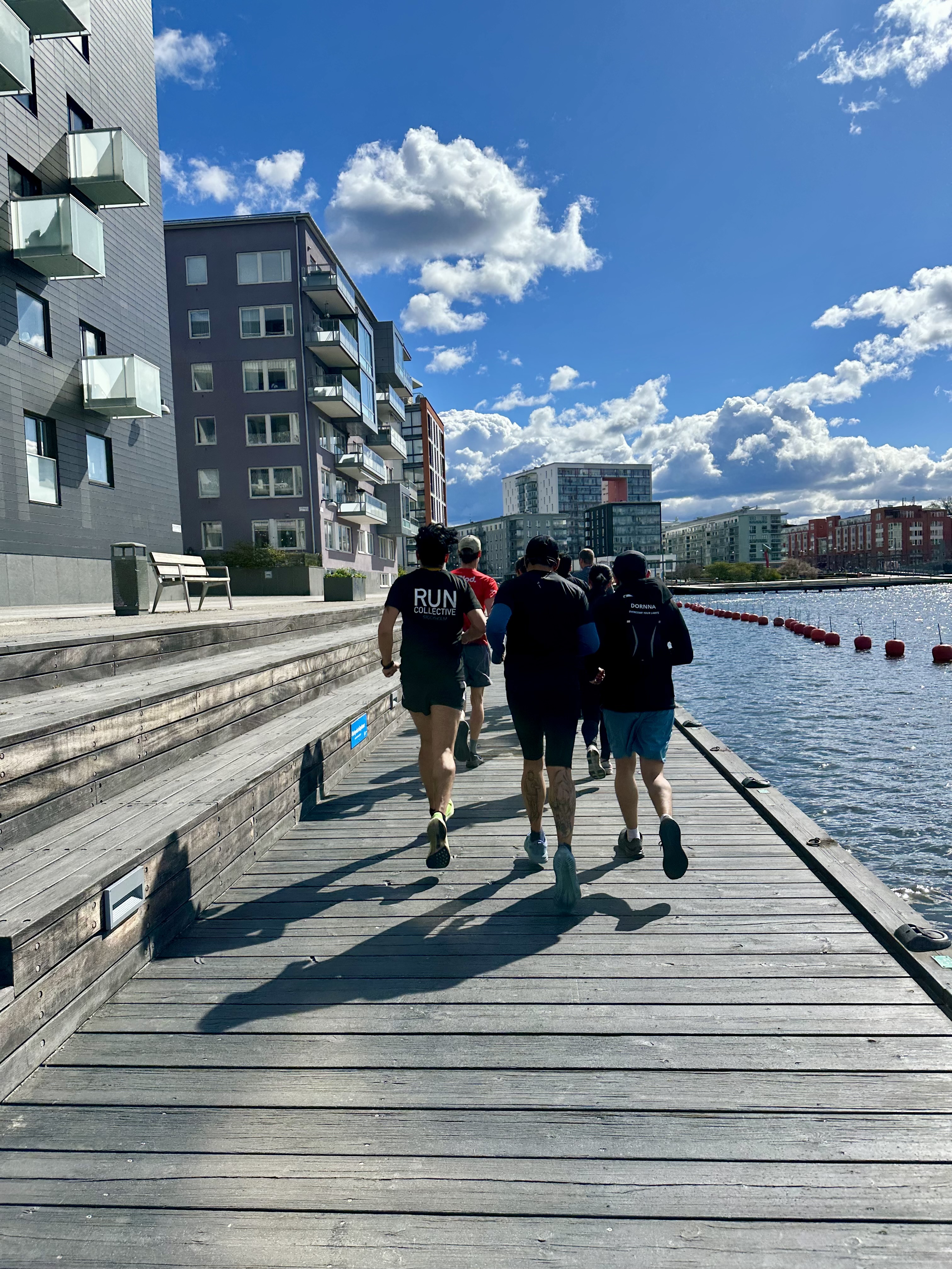 Löpargrupp springer på en brygga vid Liljeholmshamnen i Stockholm